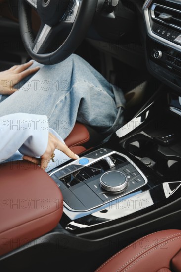 A person sits comfortably in a modern car, pressing buttons on the console with a stylish design. The interior features luxurious red leather seats and sleek controls, showcasing advanced technology, AI generated