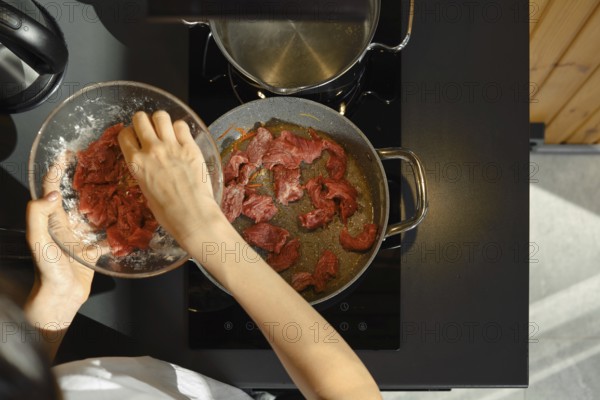 Slicing lean beef into strips and adding it to a hot pan, this skilled cook is preparing a healthy meal