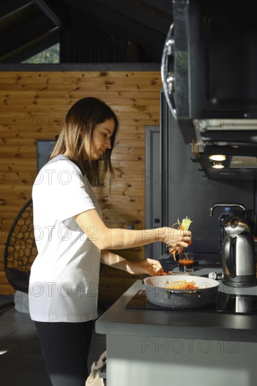 A woman prepares a healthy vegetarian dish in a charming kitchen. Bright vegetables are being added to a pot, creating a colorful and nutritious meal
