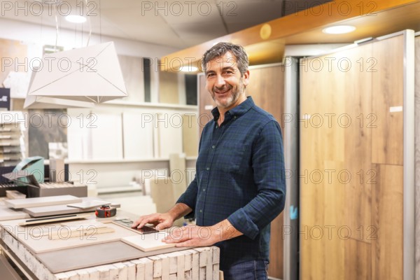 Smiling architect choosing material samples in a home improvement store, he is touching ceramic and wood tiles