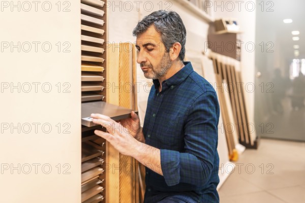 Carpenter selecting samples of wooden and metallic materials in a home improvement store for his next project