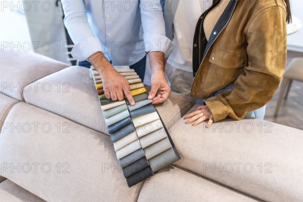 Salesman showing fabric swatches to a customer choosing upholstery for a new sofa in a furniture store