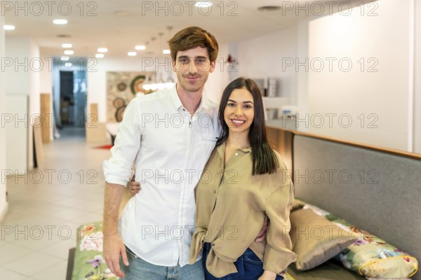 Happy couple embracing and smiling while shopping for new furniture in a vibrant home improvement store, enjoying their time together