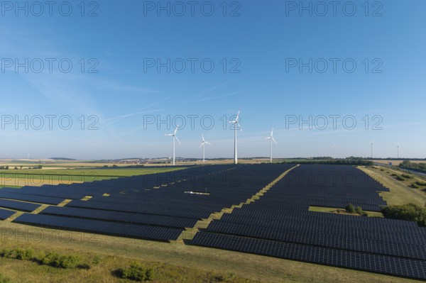 Large-scale solar panels and wind turbines across a wide agricultural field, near Kitzingen, Lower Franconia, Bavaria, Germany