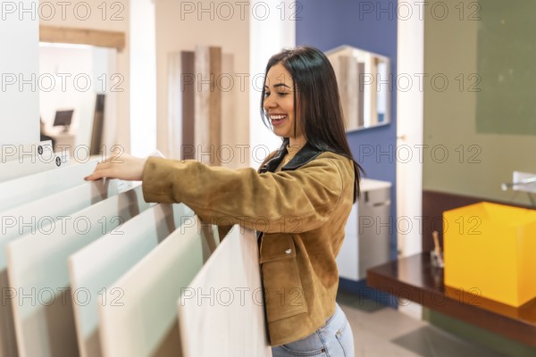 Smiling woman selecting ceramic tiles in a home improvement store, planning a bathroom renovation project