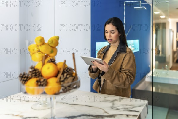 Interior designer using digital tablet while working in bathroom decor section of home improvement store showroom