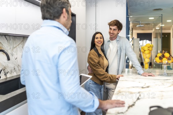 Happy couple and interior designer discussing kitchen countertop options in home improvement store showroom