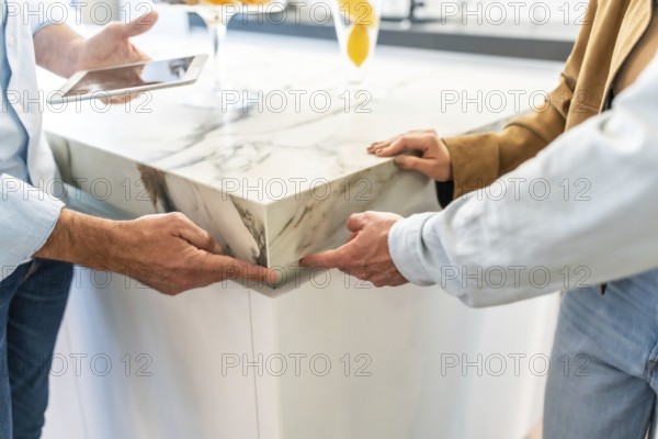 Architects examining a marble countertop joint in a home improvement store, discussing design choices while using a tablet for planning