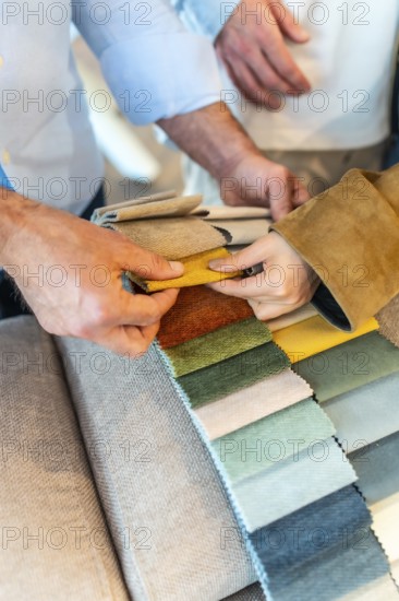 Customers and sales assistant choosing upholstery fabric from a wide variety of colors and textures in a furniture or home improvement store
