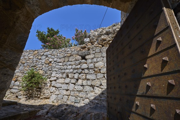 View through open Tor tor to stone wall crowned by flowers, blue sky visible, Open entrance gate, Pandeli Castle, Castle, Leros Fortress, St John's Fortress, Apitiki Hill, Pandeli Bay, Agia Marina, Leros, Dodecanese, Greek Islands, Greece