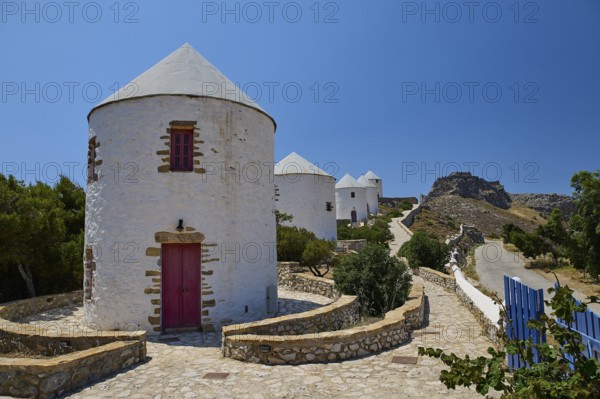 Whitewashed windmills with red doors along a stony path in the sun, Pandeli Castle, Castle, Leros Fortress, St John's Fortress, Apitiki Hill, Pandeli Bay, Windmills, Leros, Dodecanese, Greek Islands, Greece