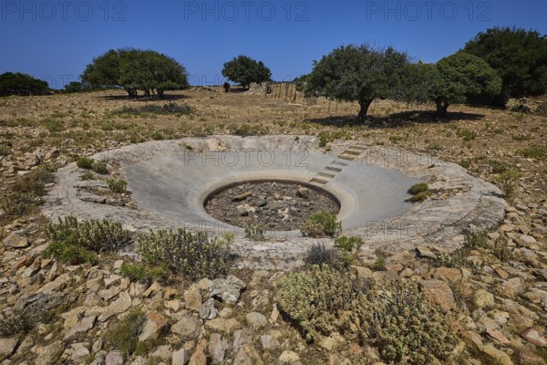 Round concrete construction in a barren landscape with trees and stones, Lost Place, Air Defence Position, Aerophone, Parabolic Acoustic Mirror, Patella Mountain, WW2, west of Lakki, Leros, Dodecanese, Greek Islands, Greece