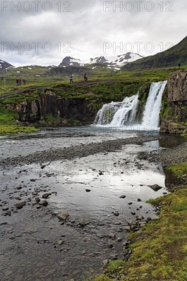 Hikers, tourists at Kirkjufellfoss waterfall, Kirkjufellsa river, Grundarfjördur, Snæfellsnes peninsula, Vesturland, Iceland