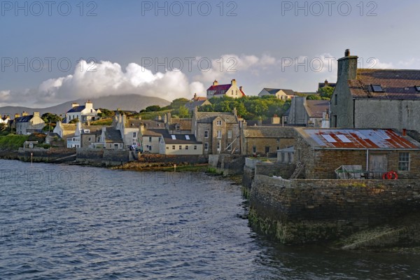 Numerous buildings at a stone harbour under a cloudy sky, Stromness, Mainland, Orkney Islands, Scotland, United Kingdom