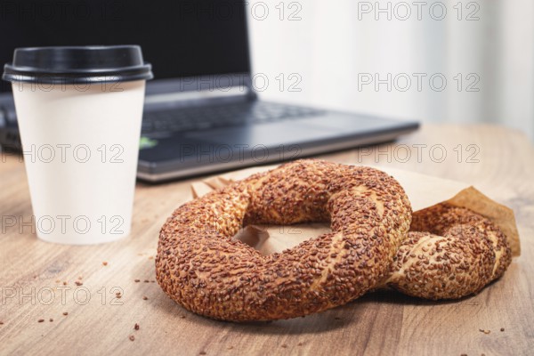 Simits with coffee on a wooden table, with a laptop, in a cozy working environment, snack, breakfast, no people