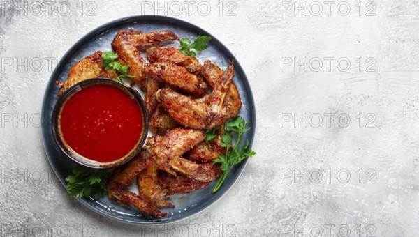 Fried in the oven, chicken wings, with spices, tomato sauce, on a plate, gray background, no people, homemade