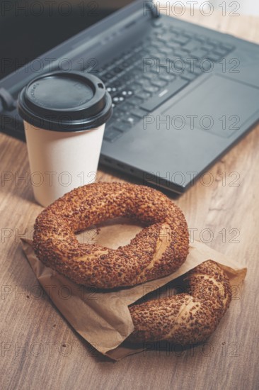 Simits with coffee on a wooden table, with a laptop, in a cozy working environment, snack, breakfast, no people