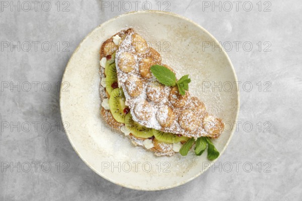 A delightful dessert featuring a crispy pastry shell filled with sliced kiwi, topped with powdered sugar and fresh mint. Enjoyed in a cozy cafe setting during a mid-afternoon treat