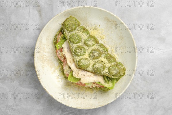 A vibrant green wrap is layered with fresh lettuce, slices of tomato, and tender chicken, resting beautifully in a white bowl. This healthy dish is perfect for a light meal or snack