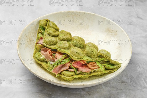 A matcha pancake showcases a vibrant green hue, folded elegantly with layers of savory ingredients such as slices of meat and fresh greens