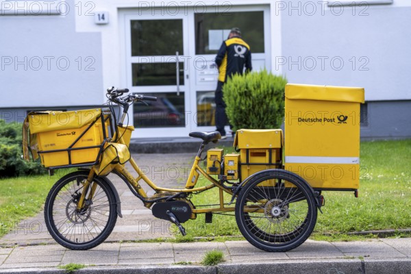 Postman, Deutsche Post, distributes the mail in an apartment building, electric tricycle, North Rhine-Westphalia, Germany