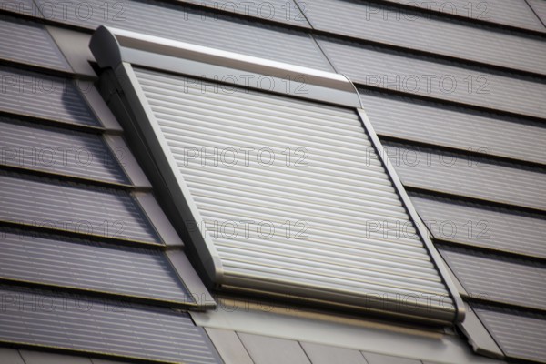 Roof window with roller shutter on a roof covered with solar tiles