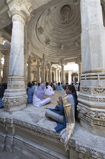 Indian woman praying between the white marble pillars in the Adinath temple in Ranakpur, Jain temple, Rajasthan, India
