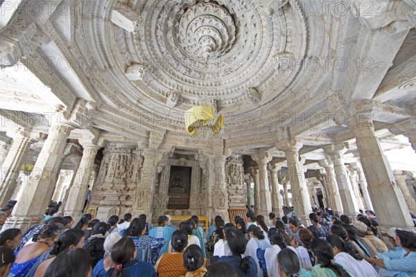 Indian woman praying between the white marble pillars in the Adinath temple in Ranakpur, Jain temple, Rajasthan, India