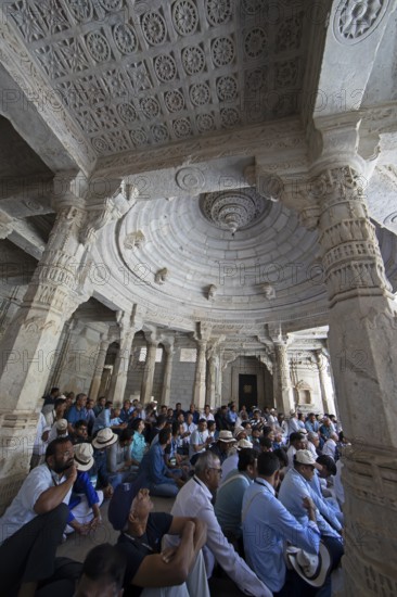 Indian men praying between the white marble pillars in the Adinath temple in Ranakpur, Jain temple, Rajasthan, India
