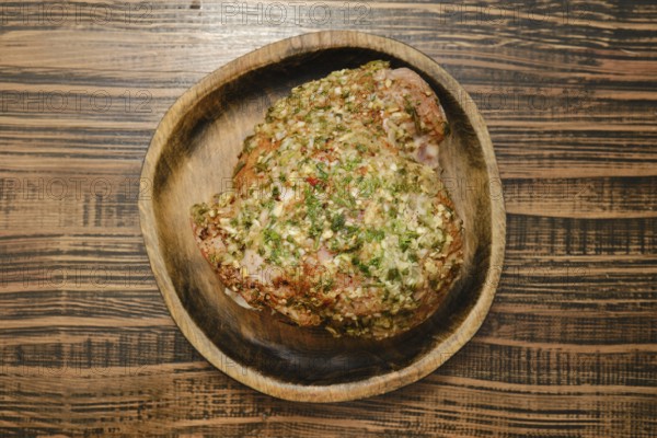 A flavorful turkey thigh is beautifully seasoned with a blend of aromatic herbs, displayed on a rustic wooden plate. This dish is perfect for a family dinner or holiday gathering