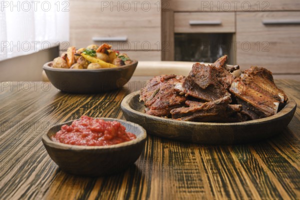 Succulent roasted beef ribs are plated alongside a vibrant vegetable medley and a bowl of spicy sauce