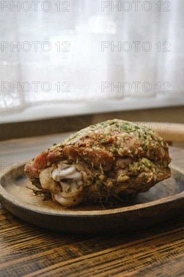 Juicy roasted turkey thigh with herbs on a wooden plate in a cozy kitchen setting