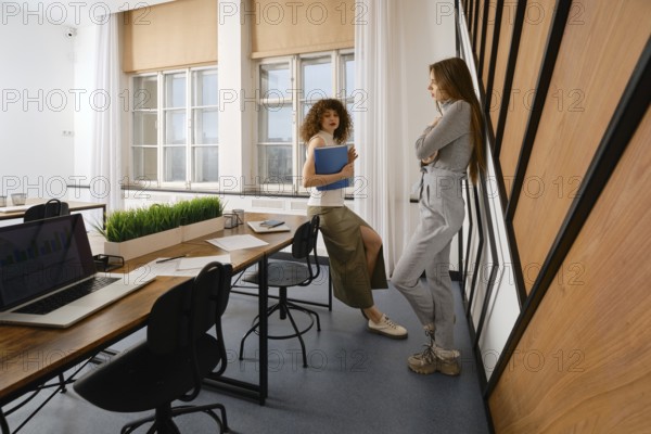 Two women are discussing the user interface of their health monitoring app in a stylish startup office