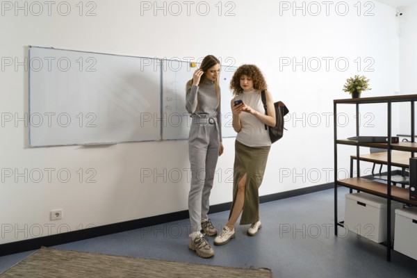 Women have finished work in coworking and call a taxi online using a mobile application in a smartphone