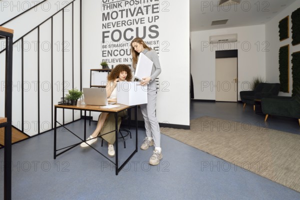 A woman looks into a box with the archives that her colleague brought to modern coworking