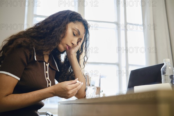 A woman experiences pain during menstruation and is forced to take painkillers while working remotely in her home office