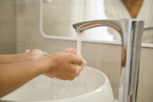 Water flows from a sleek faucet as hands are lathered with soap in a bathroom setting, emphasizing the importance of cleanliness and personal care in daily routines