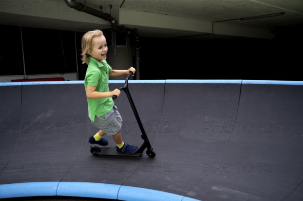 Boy, 6 years, blond, rides scooter, scooter, pump track, laughs, joy, Stuttgart, Baden-Württemberg, Germany