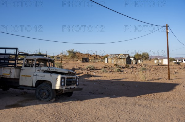 Old transport vehicle and simple houses made of wood and mud in a small village, Erongo, Damaraland, Namibia