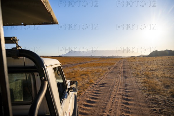 View from a safari vehicle, sandy track in desert landscape, in the evening light, Brandberg, Erongo, Damaraland, Namibia