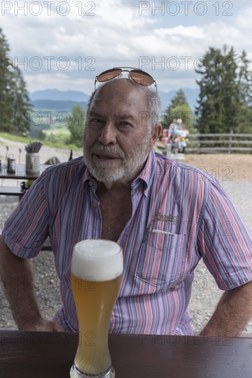 Elderly man with beard and sunglasses in a garden restaurant with a drink, Bavaria, Germany