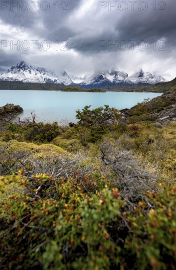 Cloudy mountain range Cuernos del Paine, shore of the blue lake Lago Pehoe in the evening light, dramatic sky, Torres del Paine National Park, Chile