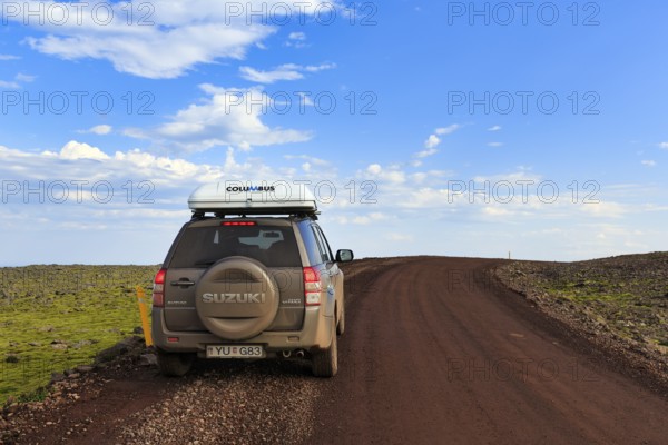 SUV Suzuki Grand Vitara with roof tent, travelling on a gravel road, Cumulus, Latrabjarg headland, Westfjords, Iceland