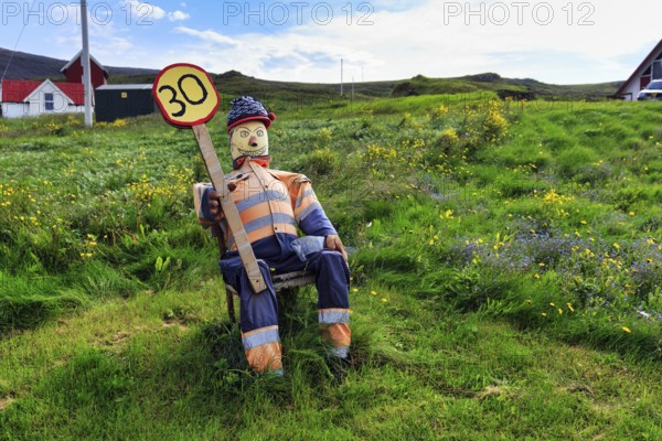 Funny traffic control, 30 km/h, speed limit, figure sits on summer meadow and holds self-made traffic sign, Latrabjarg headland, Westfjords, Iceland