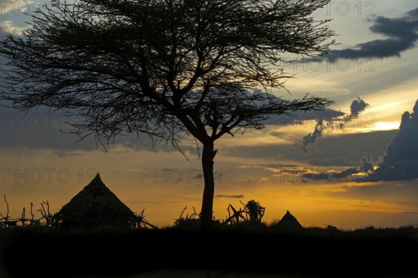 Silhouette of conical huts of the Hamer ethnic group against a dramatic sunset sky, Southern Omo Valley, Ethiopia