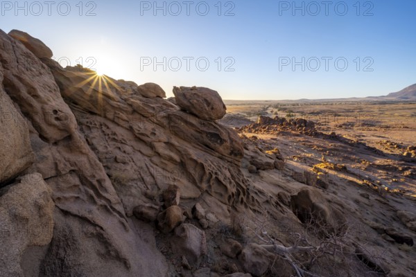 Eroded rock formations at sunrise with sun star, Erongo, Damaraland, Namibia