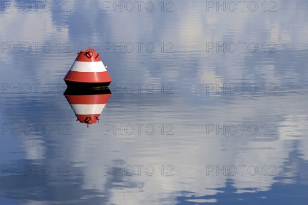 Red and white buoy and blue cloudy sky reflected on the surface of the water, Möhne Reservoir, North Rhine-Westphalia, Germany