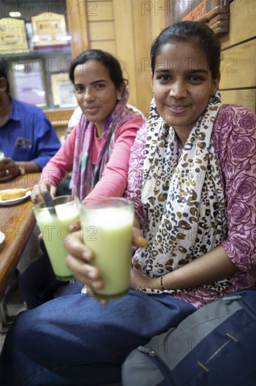 Indian woman drinking lassi or yoghurt drinks in a shop at Sandar Market Girdikot, old town of Jodhpur, Rajasthan, India