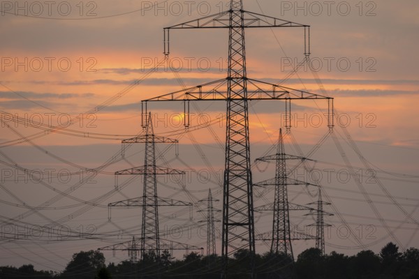 Close-up of electricity pylons against a brilliant orange evening sky, Waiblingen, Baden-Württemberg, Germany