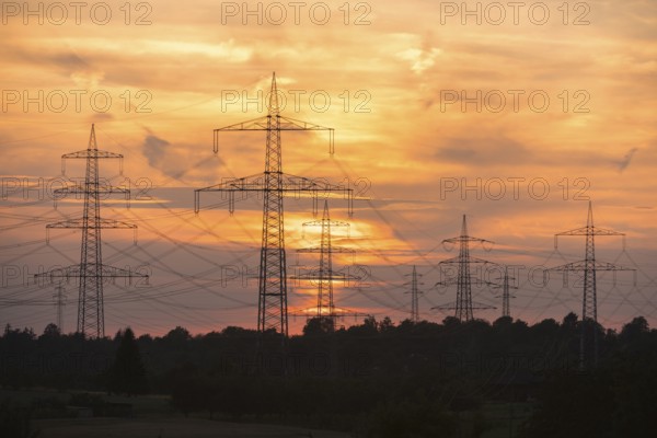 Sunset with electricity pylons and orange sky in a rural setting, Waiblingen, Baden-Württemberg, Germany